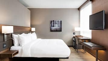 Una habitación de hotel moderna con una cama grande, mesitas de noche, un escritorio y un televisor.