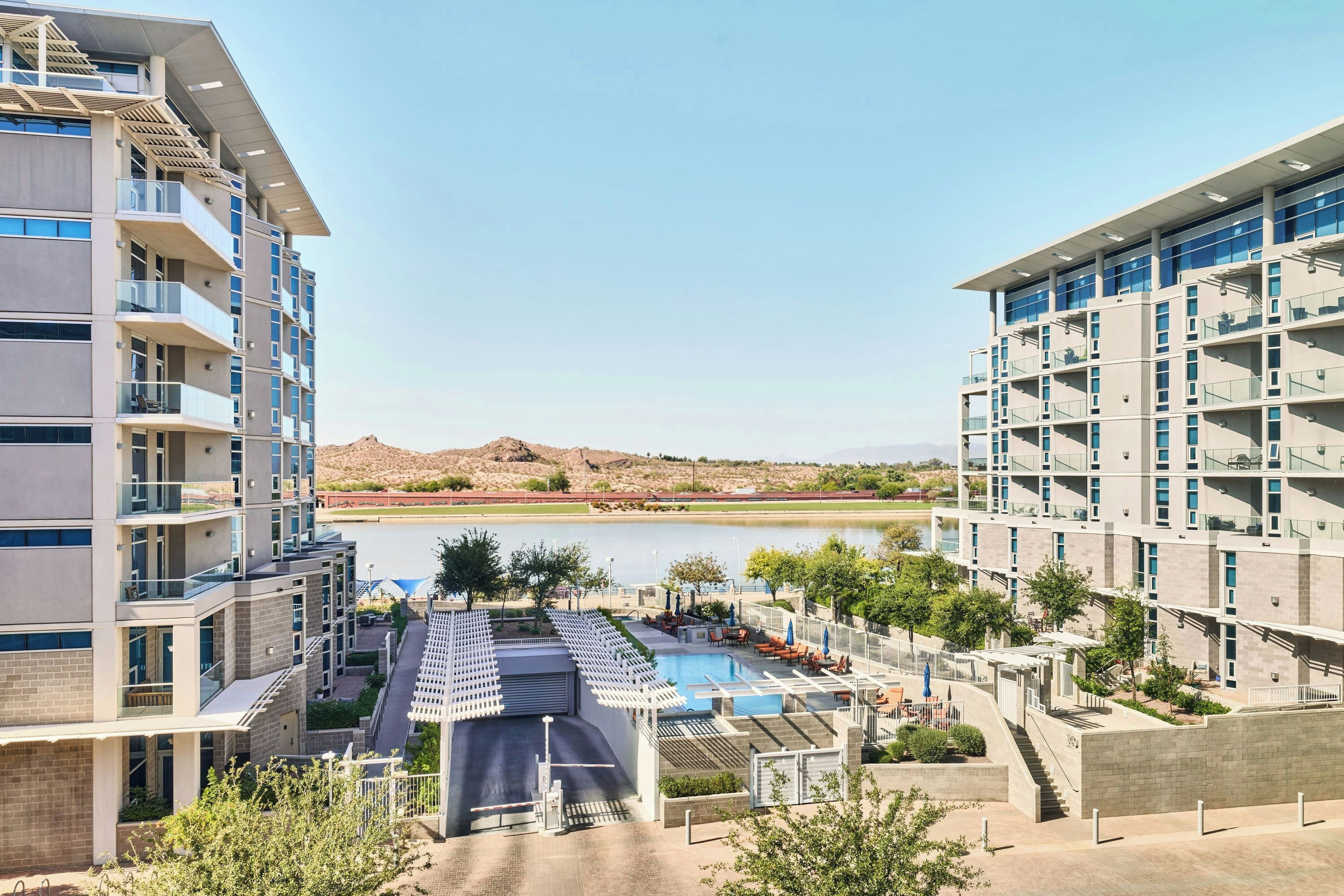 Un hôtel moderne à plusieurs étages, doté d’une piscine et offrant une vue sur un lac et des montagnes.