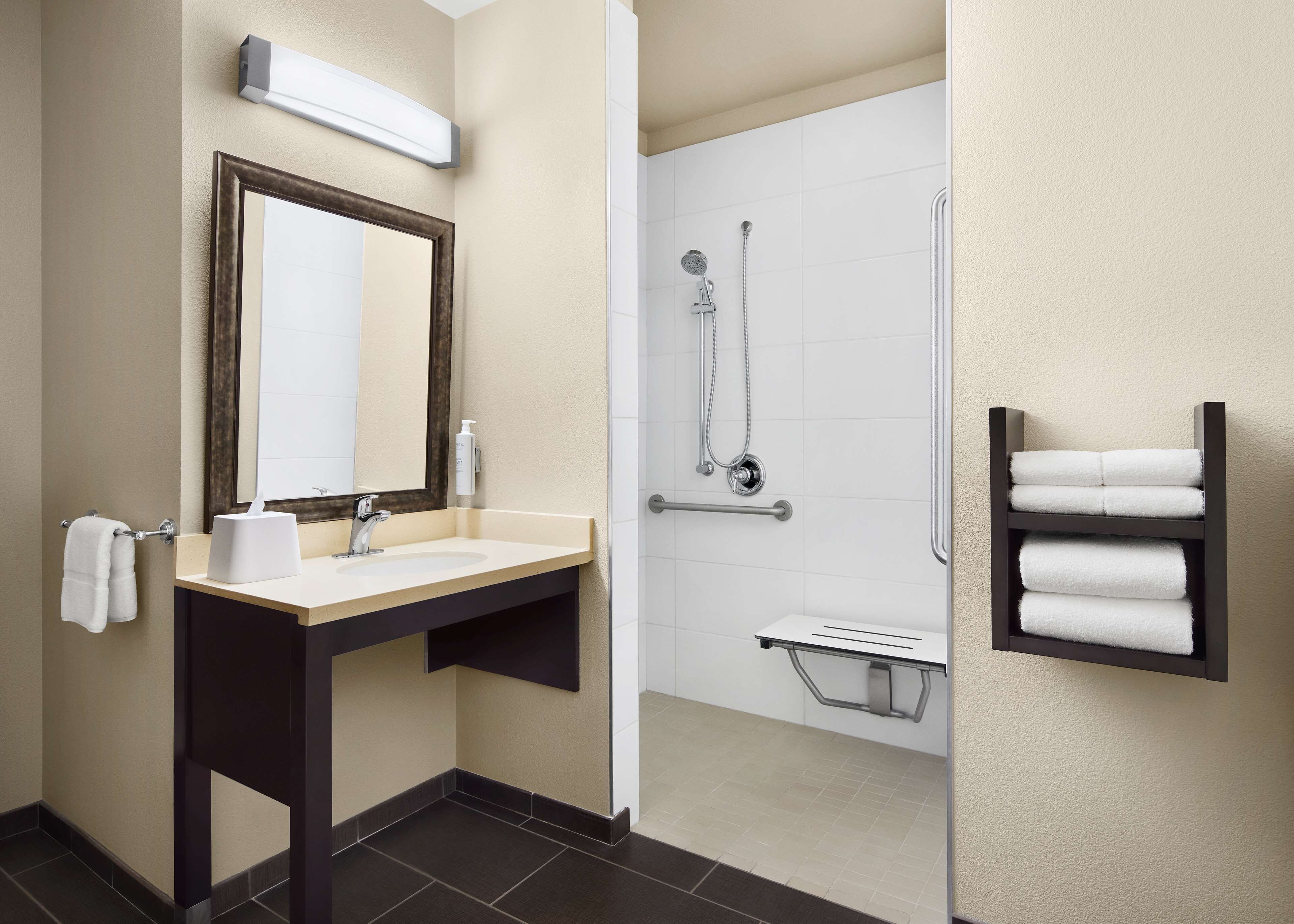 Een moderne badkamer met een wastafel, spiegel, handdoekhouder en douche.