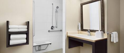 A modern bathroom with a shower, a sink, a mirror, and a towel rack.