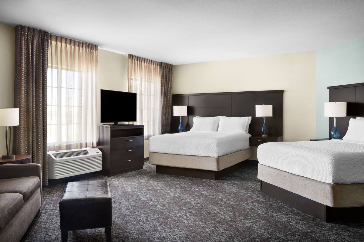 Une chambre d’hôtel avec un grand lit, deux tables de chevet avec des lampes, un téléviseur à écran plat, un radiateur et un petit coin salon.