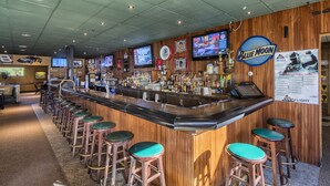 A bar area with wooden bar counters, green cushioned stools, and multiple televisions displaying sports content. - Sleep Inn & Suites Syracuse Airport (East Syracuse)