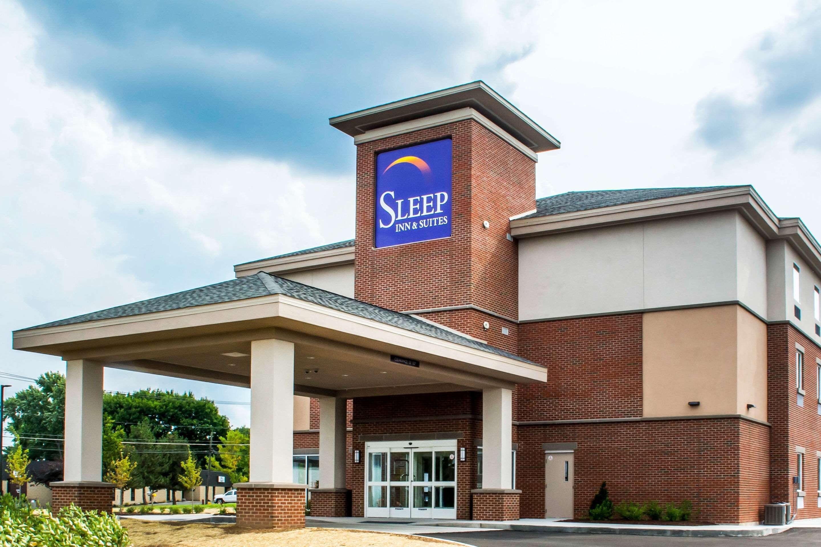 A Sleep Inn & Suites building with a prominent sign, a covered entrance, and a brick facade.