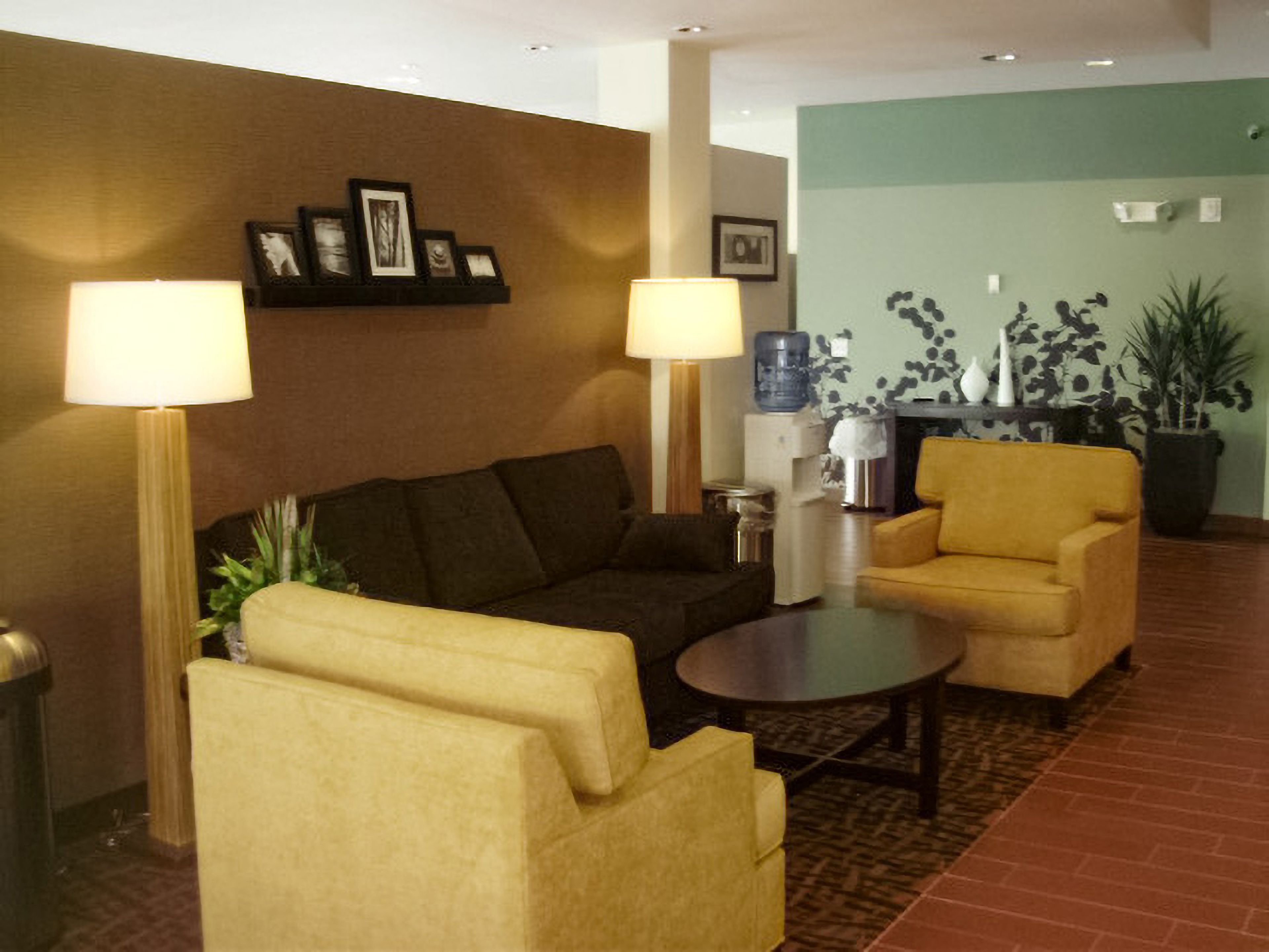 A lobby with a sofa, armchairs, a coffee table, and a water dispenser.
