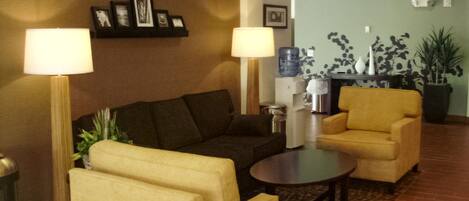 Eine Lobby mit einer Couch, Sesseln, einem Couchtisch und einem Wasserspender.