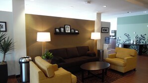 A modern lobby with a brown sofa, two yellow armchairs, a coffee table, and two floor lamps. - Sleep Inn & Suites Syracuse Airport (East Syracuse)