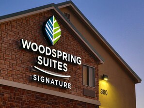 A hotel sign with the name "Woodspring Suites Signature".