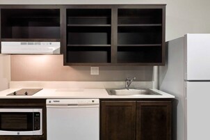 Una cocina equipada con microondas, lavavajillas y un lavamanos con grifo.