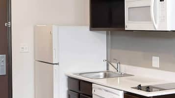 Una cocina compacta con un refrigerador blanco, un microondas sobre la encimera, un fregadero y un lavavajillas.
