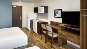 A hotel room with two beds, a kitchenette, a desk, and a TV. - WoodSpring Suites Houston IAH Airport (Humble)