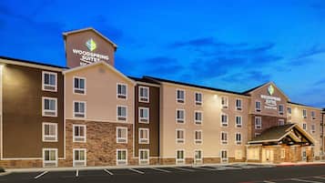 Un hôtel à plusieurs étages, avec une enseigne indiquant « Woodspring Suites Signature ».