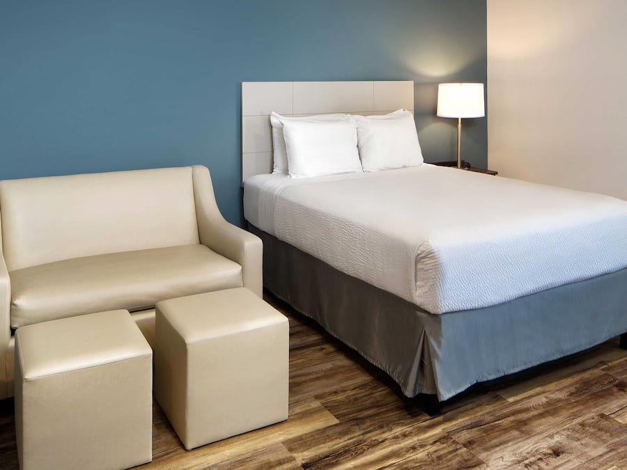 Een hotelkamer met een bed, een slaapbank en een nachtkastje met een lamp.