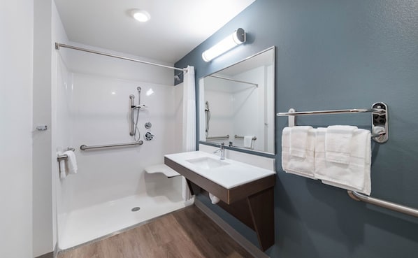 A modern bathroom with a walk-in shower, a sink, and a large mirror. - WoodSpring Suites Houston IAH Airport (Humble)
