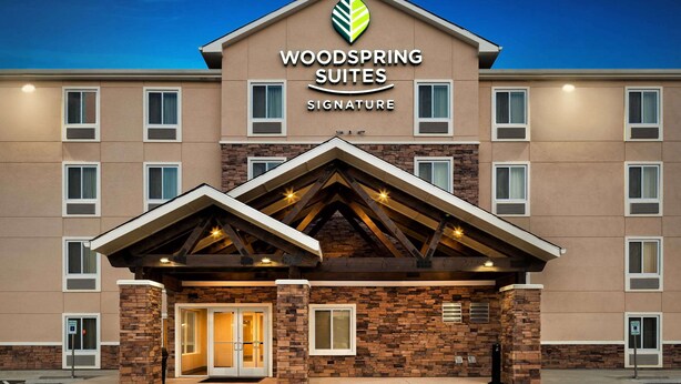 A hotel entrance with a sign reading "Woodspring Suites Signature." - WoodSpring Suites Houston IAH Airport (Humble)