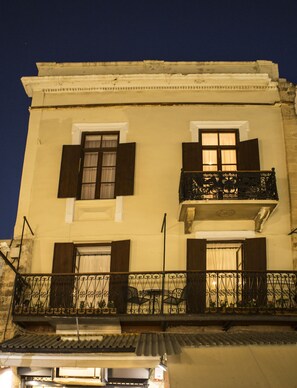 A building with a balcony, windows with shutters, and a tiled roof. - Favela Living Space (Chania)