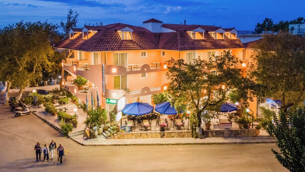 A hotel with multiple floors, outdoor seating, and a paved entrance area.