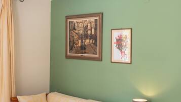 A room with a bed, a nightstand, a lamp, and two framed pictures on the wall.