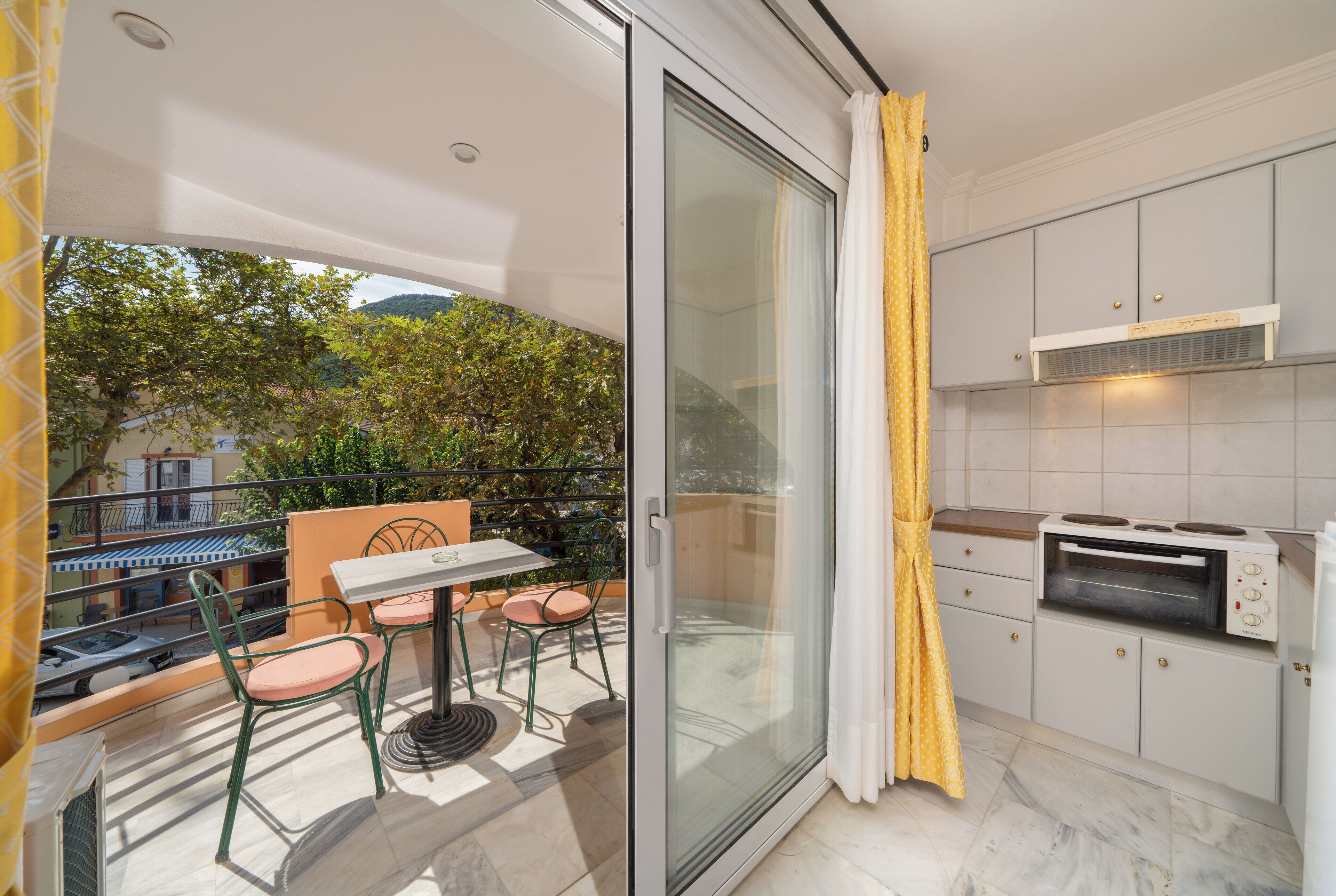 Ein Balkon mit Tisch und Stühlen, eine Schiebetür und eine Küche mit Einbauofen.