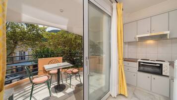 Ein Balkon mit Tisch und Stühlen, eine Schiebetür und eine Küche mit Einbauofen.