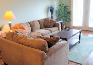 A living room with a sofa, a coffee table, a lamp, and a potted plant. - Celebration Cove Table Rock Lakefront Condos (Branson)