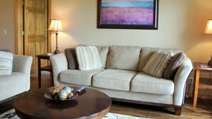 Un soggiorno con un divano beige, un tavolino da caffè con oggetti decorativi e un quadro appeso alla parete.