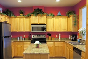 A kitchen with wooden cabinets, a stainless steel refrigerator, a microwave, an oven, and a granite countertop. - Celebration Cove Table Rock Lakefront Condos (Branson)