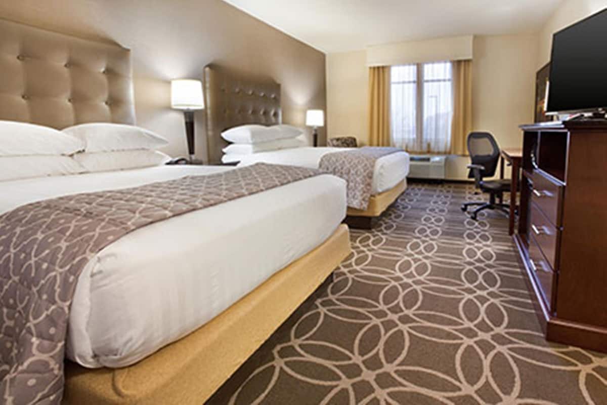 A hotel room with two beds, a TV, a desk, and a dresser.