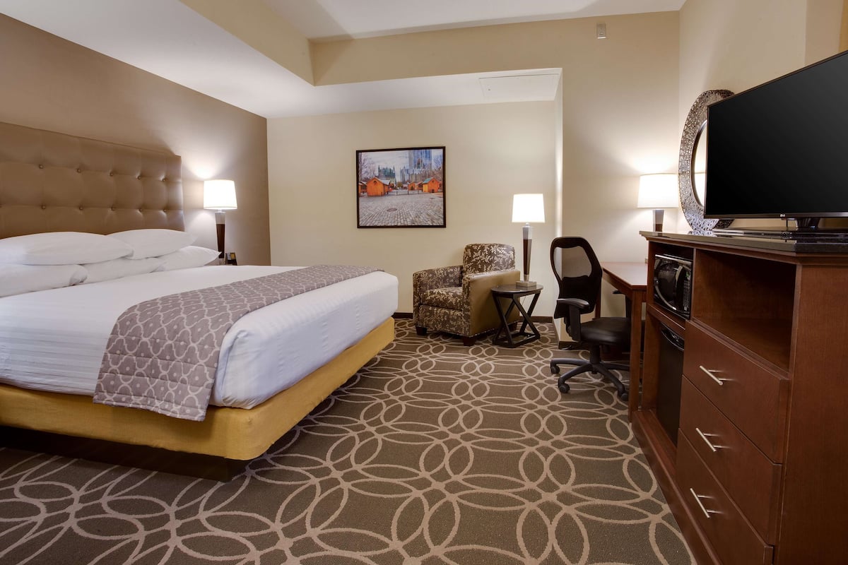 A hotel room with a large bed, a desk with a computer, a television, and a chair.