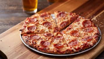 Een pepperoni pizza op een metalen bord op een houten tafel.