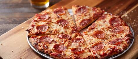 A pepperoni pizza on a metal plate on a wooden table.