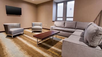 A modern living room with a sofa, two armchairs, a coffee table, and a flat-screen TV mounted on the wall.