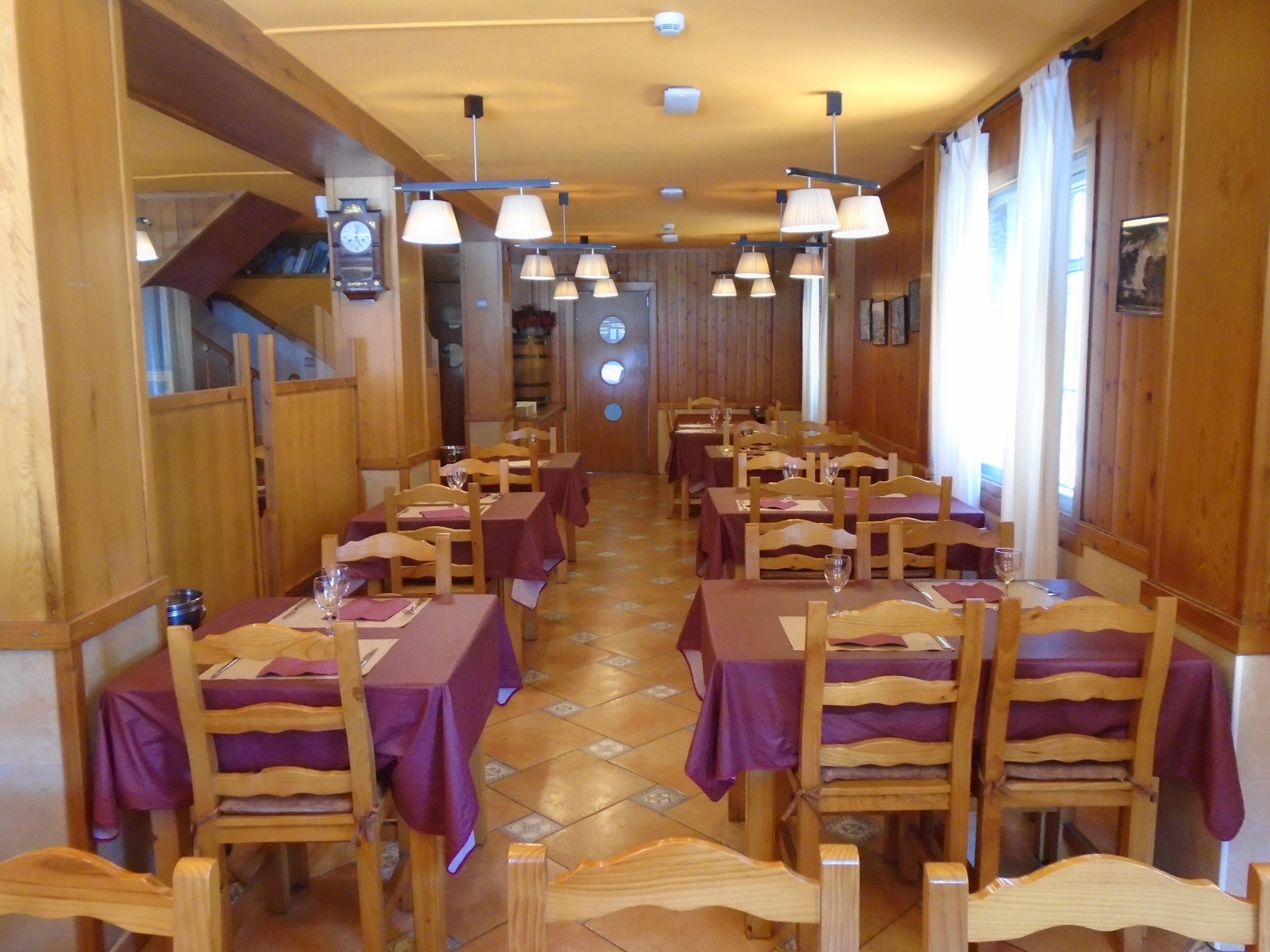 A restaurant with wooden walls and tables set with purple tablecloths and wooden chairs.