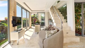 A modern living room with a sofa, TV, and a staircase leading to an upper level. - Echo Beach Resort (Canggu)