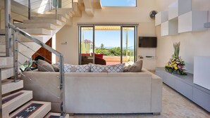 A modern interior with a staircase, a sofa, and a TV. - Echo Beach Resort (Canggu)
