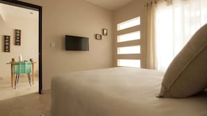 Un dormitorio con cama, televisor montado en la pared y ventana con cortinas.