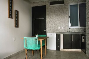 Una cocina compacta con una mesa y sillas, una puerta negra y una ventana.