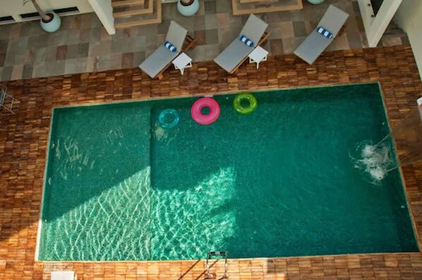 Una piscina rectangular rodeada por una terraza de madera.