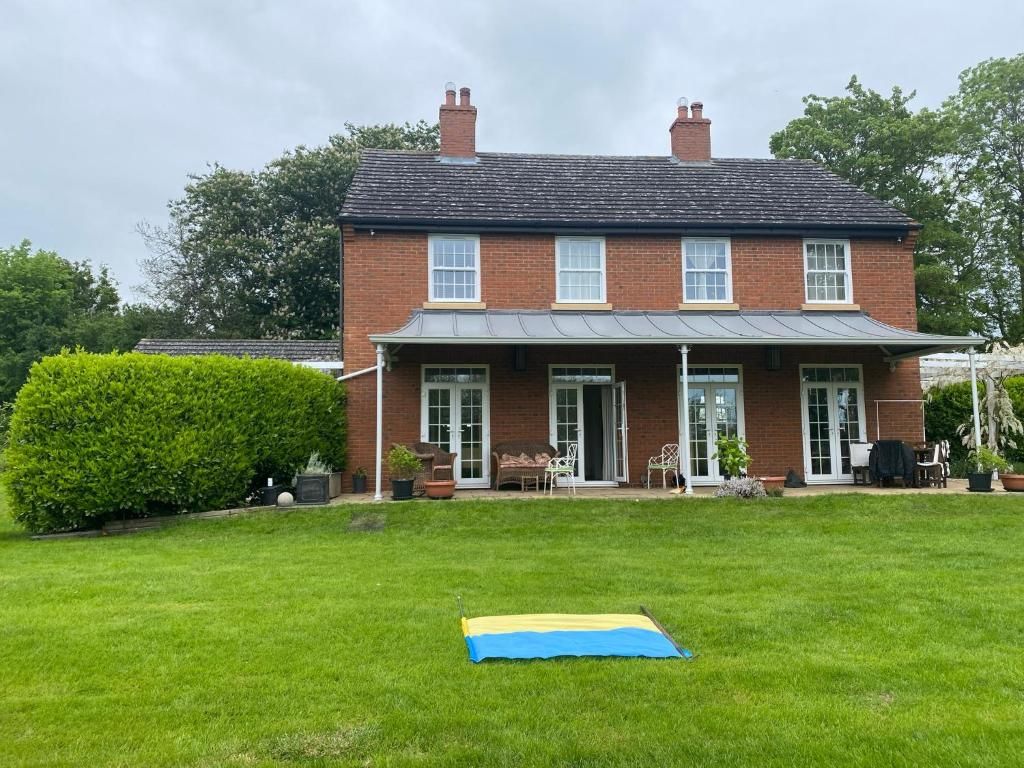 A two-story house with a front porch, a lawn, and a trampoline.