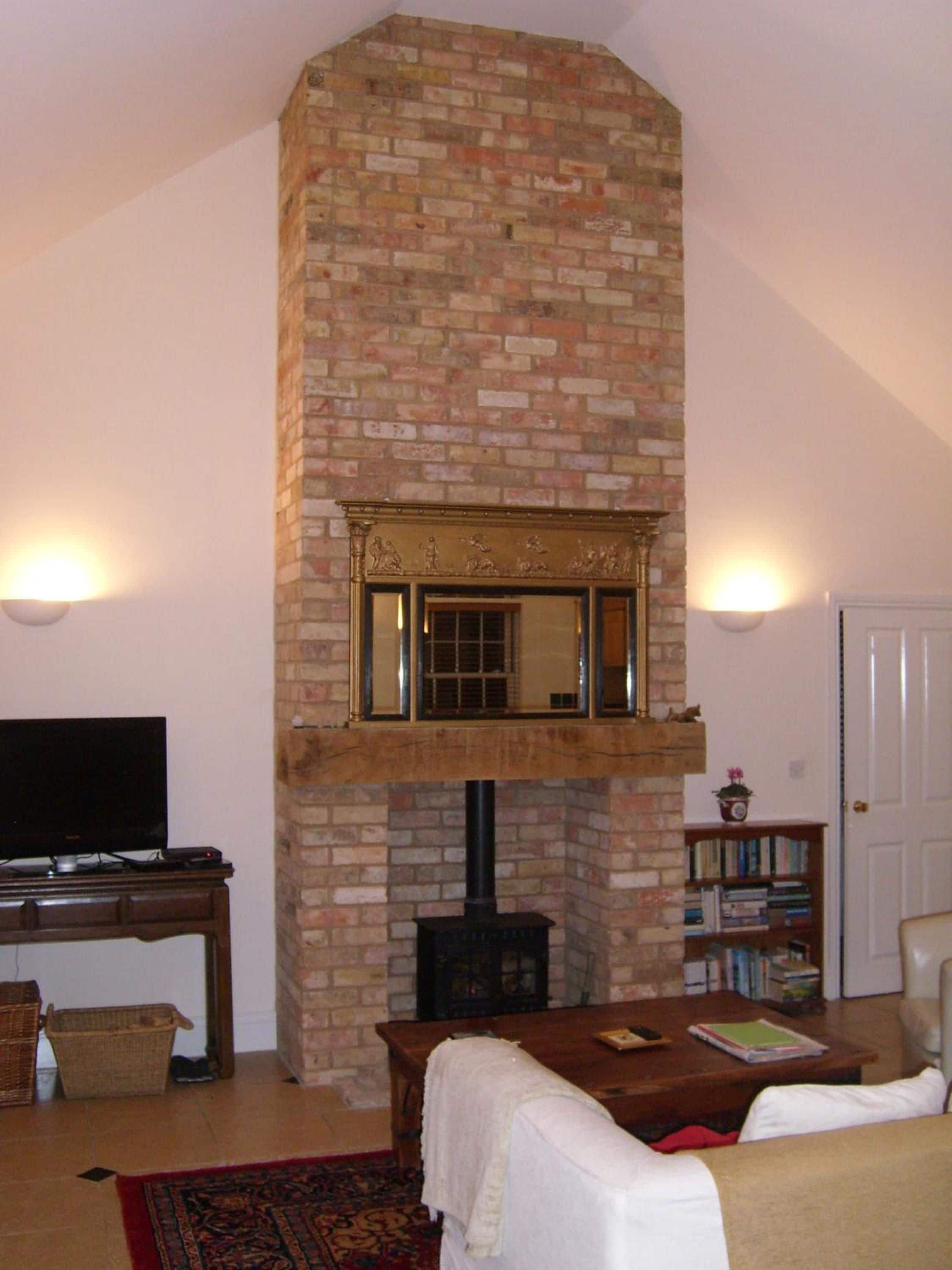 Una sala de estar con chimenea de ladrillo, televisor, estantería y una puerta.