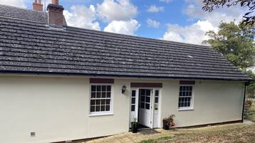 A single-story house with a tiled roof, a front door, and two windows.