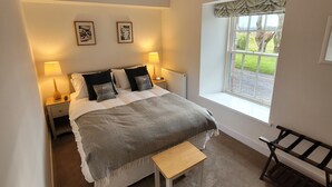 Un dormitorio con cama, lámparas de noche, una ventana con vistas y un banco.