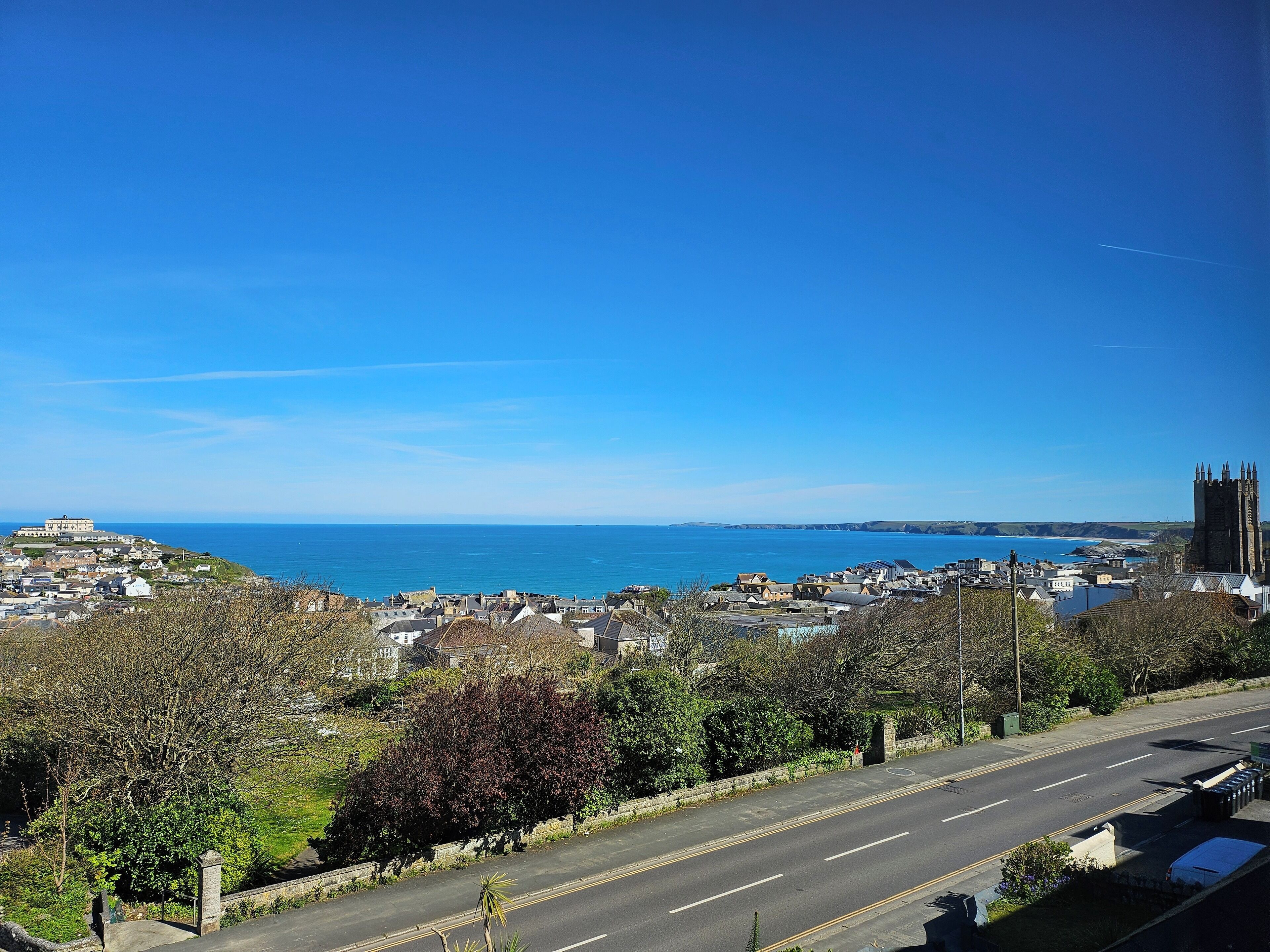 Eine Küstenstadt mit einem markanten, schlossartigen Bauwerk, blauem Himmel und Blick aufs Meer.
