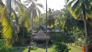 A thatched-roof hut surrounded by lush greenery and palm trees. - Finca La Jorará (Santa Marta)