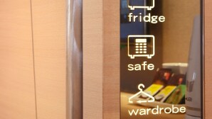 A mirror with icons indicating a fridge, safe, and wardrobe. - Guest Hotel (Taipei)