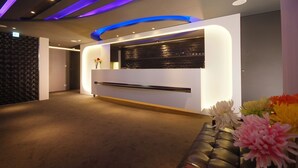A reception area with a modern design, featuring a reception desk, a wall-mounted display, and a carpeted floor. - Guest Hotel (Taipei)