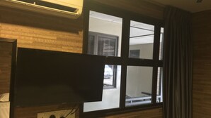 Una habitación con un ventanal grande, un televisor de pantalla plana montado en la pared y un enchufe.