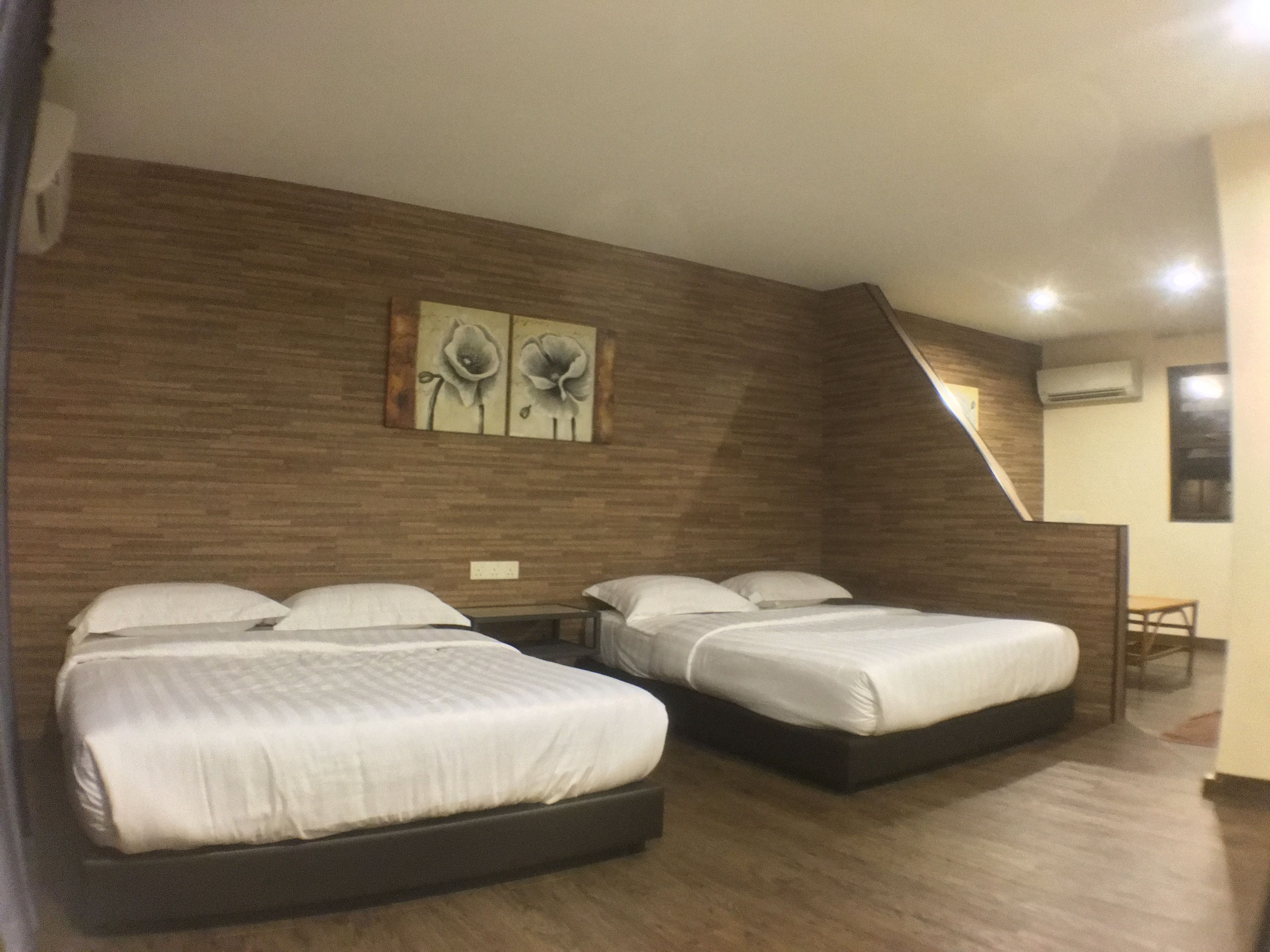 Quarto de hotel com duas camas, paredes de madeira e uma pequena mesa.