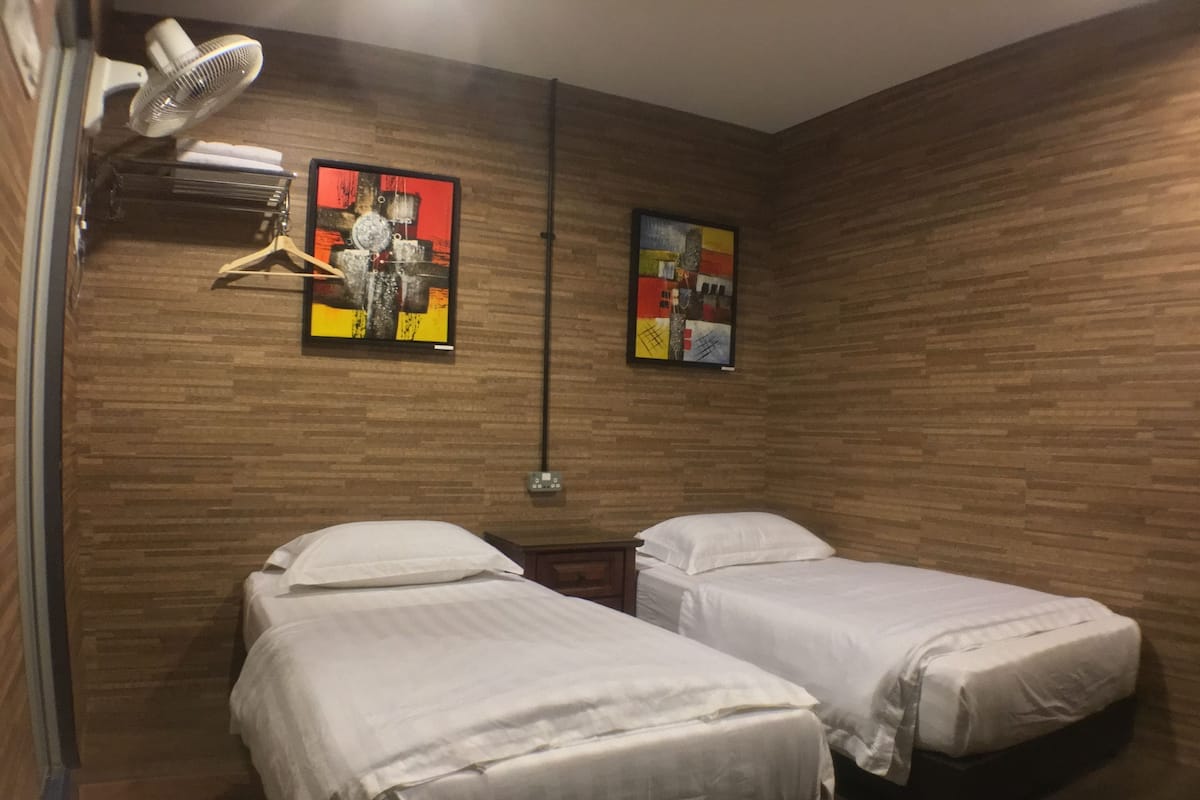 Una habitación con dos camas, paredes de madera y dos cuadros abstractos.