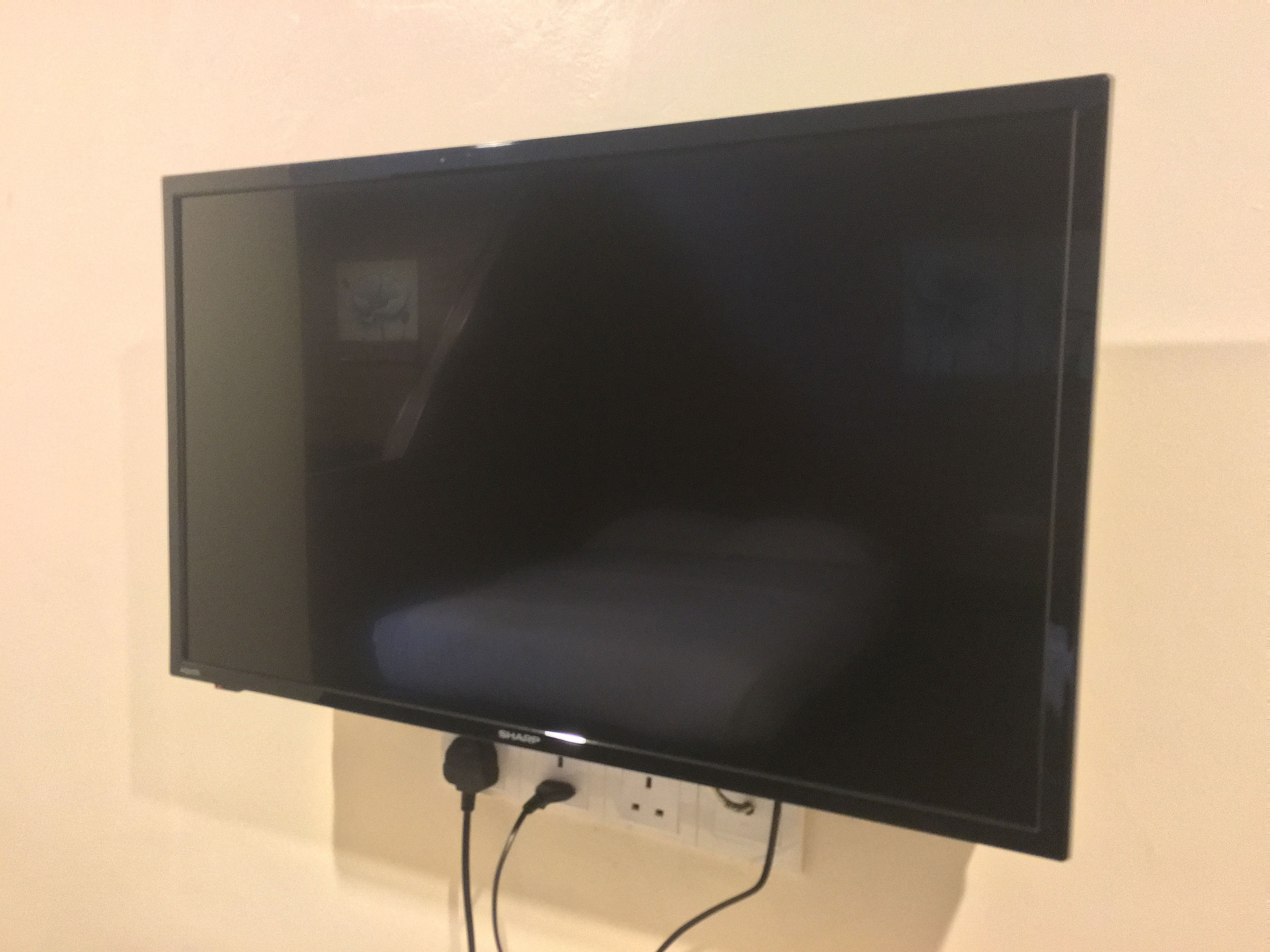 Un televisor de pantalla plana sujeto a la pared, con dos cables a la vista.