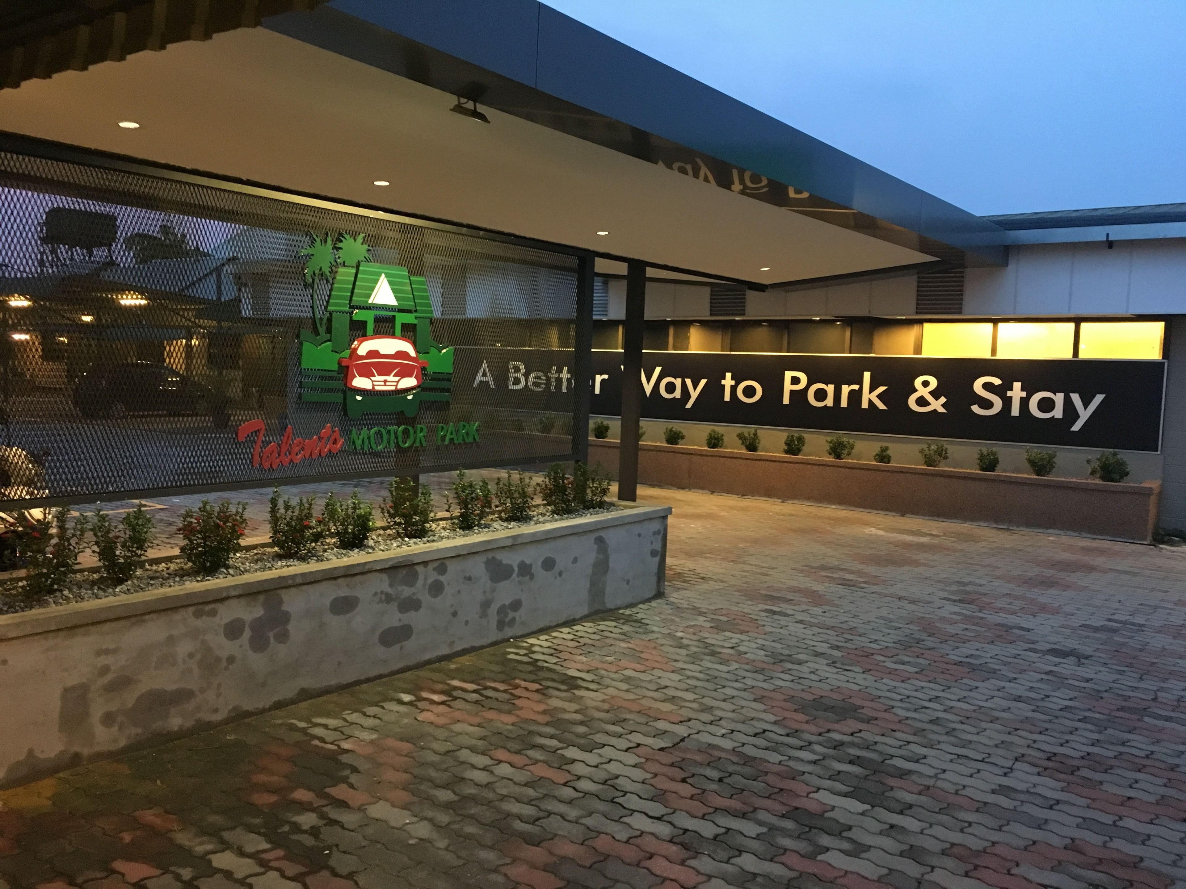 A hotel entrance with a sign reading "A Better Way to Park & Stay" and a logo for "Tabby's MOTOR PARK".